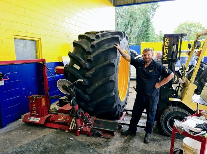 Mechanic Standing Beside Large Tractor Tyre — Goodyear Auto Care In Toowoomba, QLD